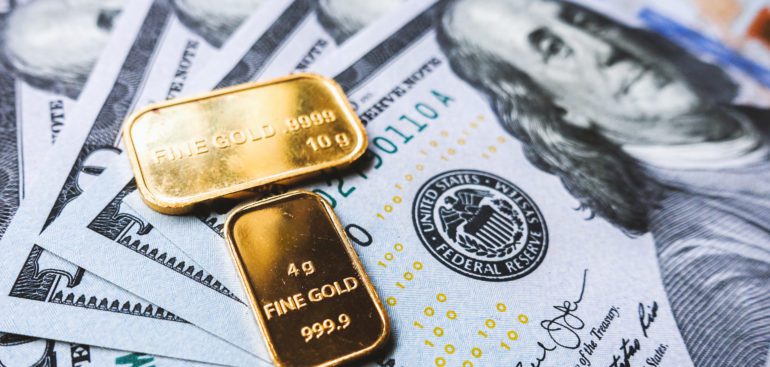 Gold Bars lying On Top Of One Hundred Dollar Bills