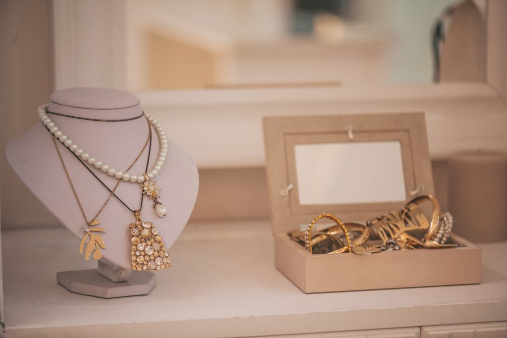 Luxury gold jewelry on set holders and in jewelry box on light dressing table and wardrobe shelves