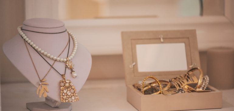 Luxury gold jewelry on set holders and in jewelry box on light dressing table and wardrobe shelves